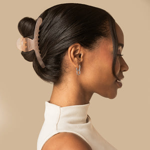 Model wearing the kitsch translucent Soft Pink Arched Claw Clip - Large securing dark hair in a sleek updo